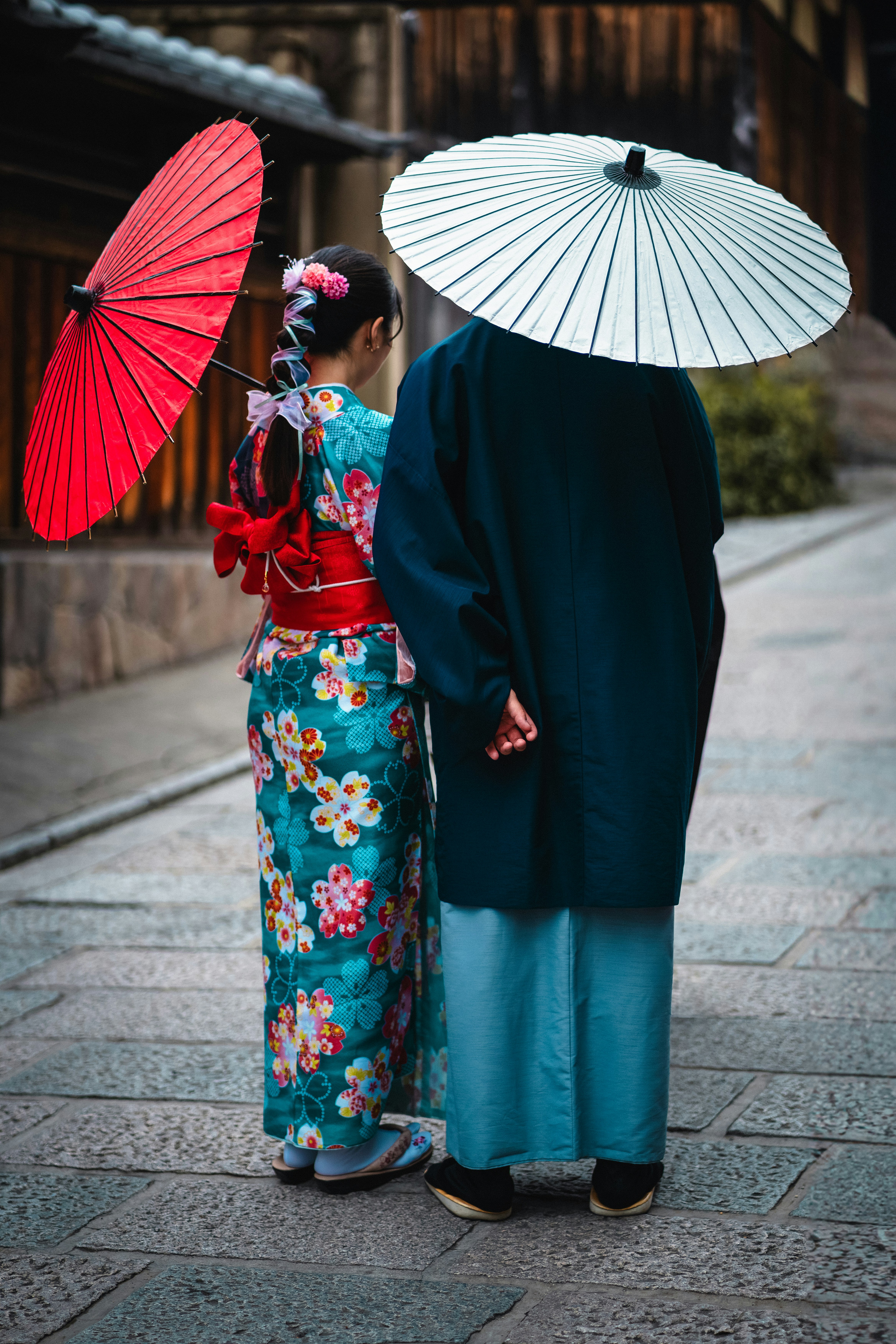 Couple in kimono holding umbrellas near a temple